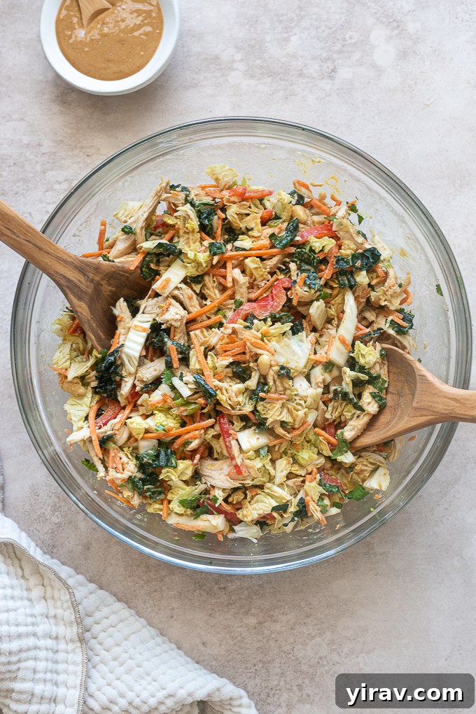 Thai chicken salad with peanut dressing tossed in a mixing bowl.