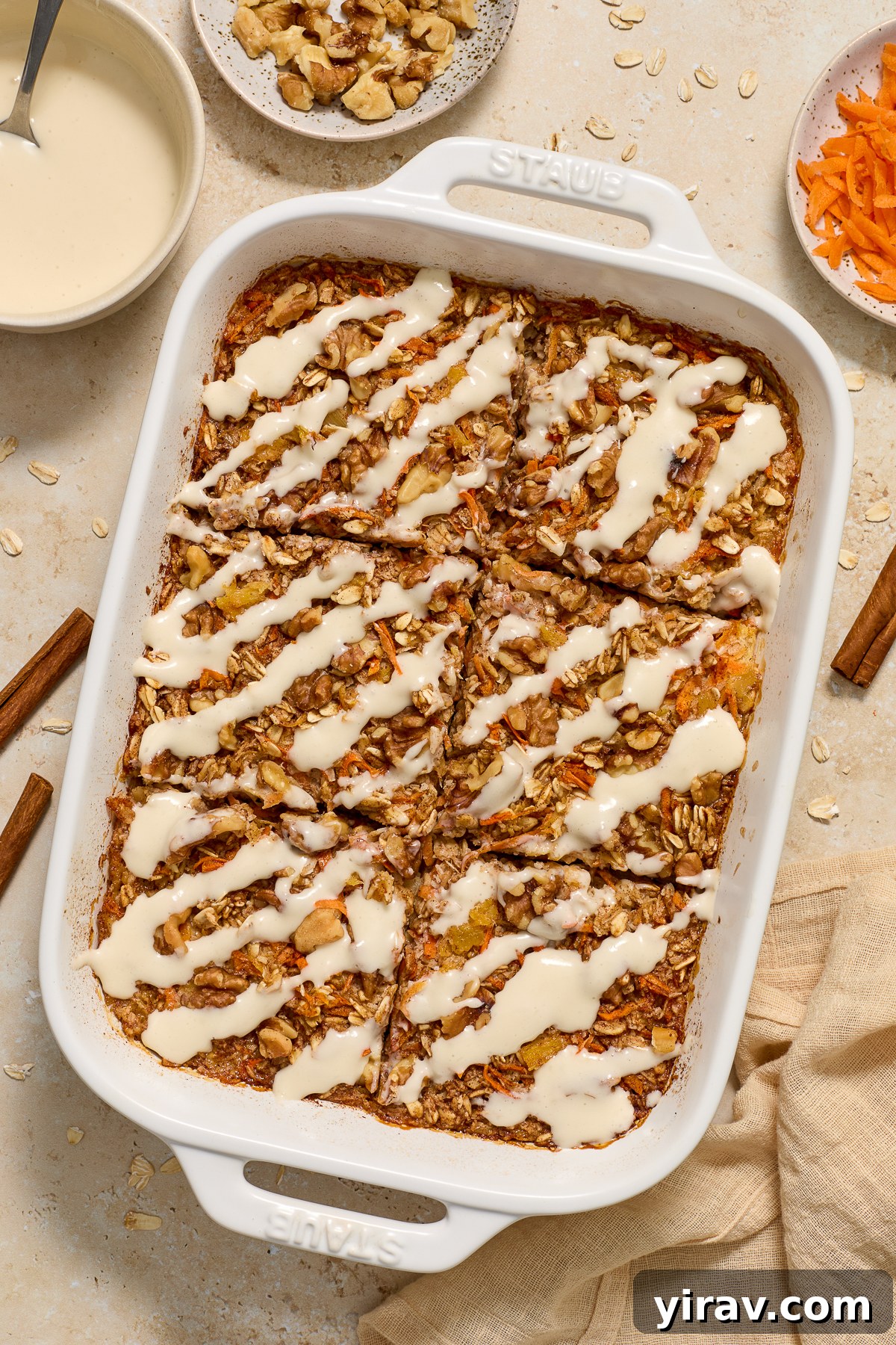 Carrot Cake Baked Oatmeal topped with cream cheese glaze in baking dish.