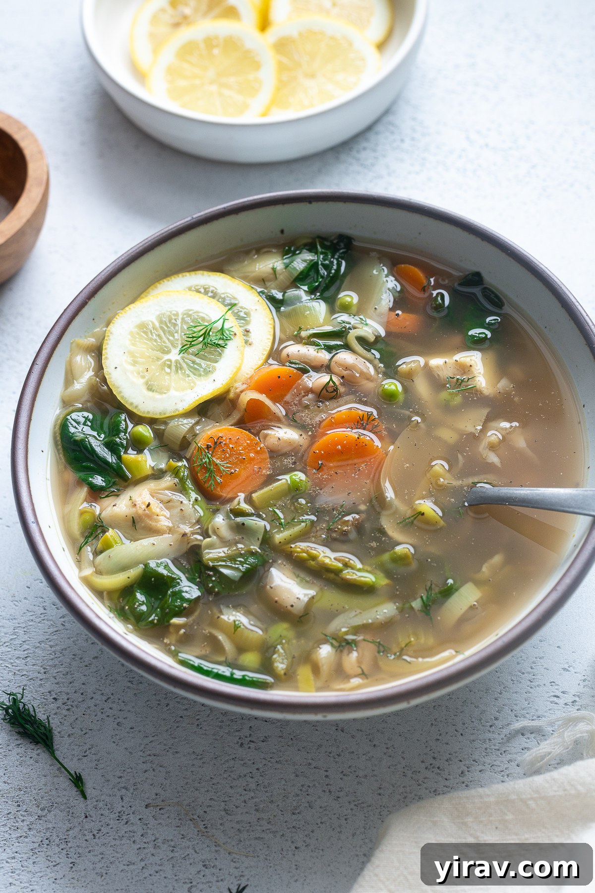 Spring vegetable soup in a bowl with lime slices on top.