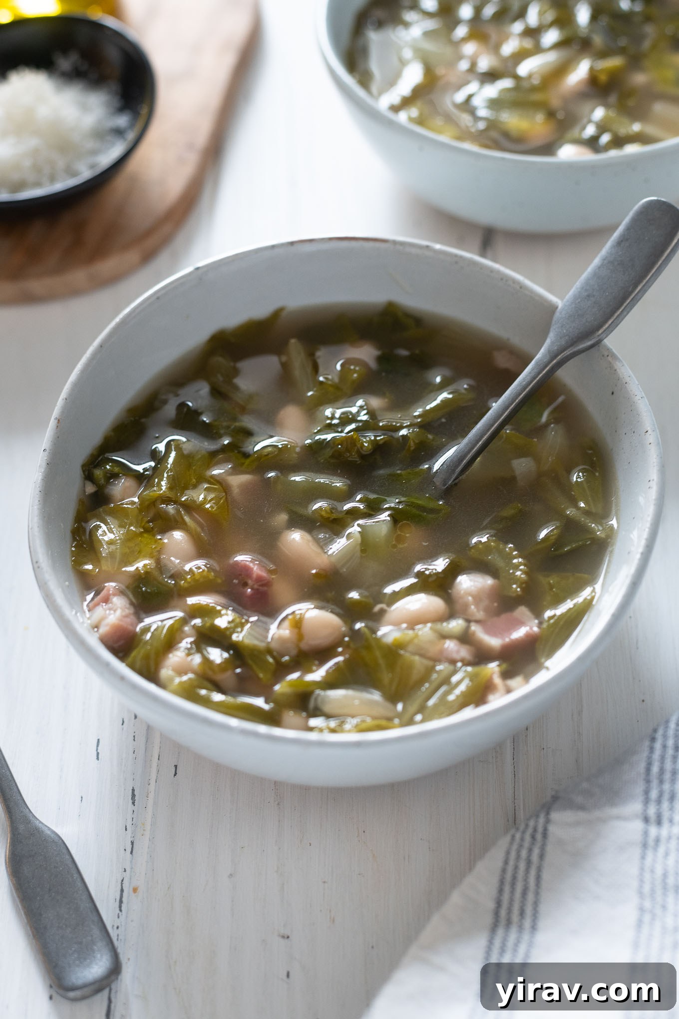 Bowl of escarole and bean soup with spoon buried inside