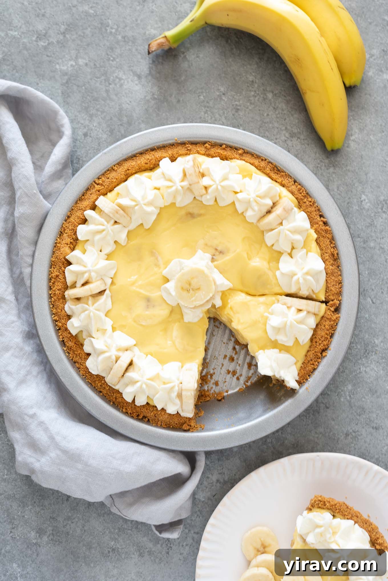 Banana cream pie with serving on a plate nearby
