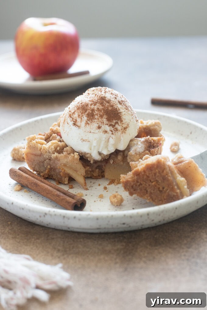 Golden Crumb Apple Pie Bars 10 Apple Pie Bars with shortbread crust and crumb topping on white plate, ready for a bite.