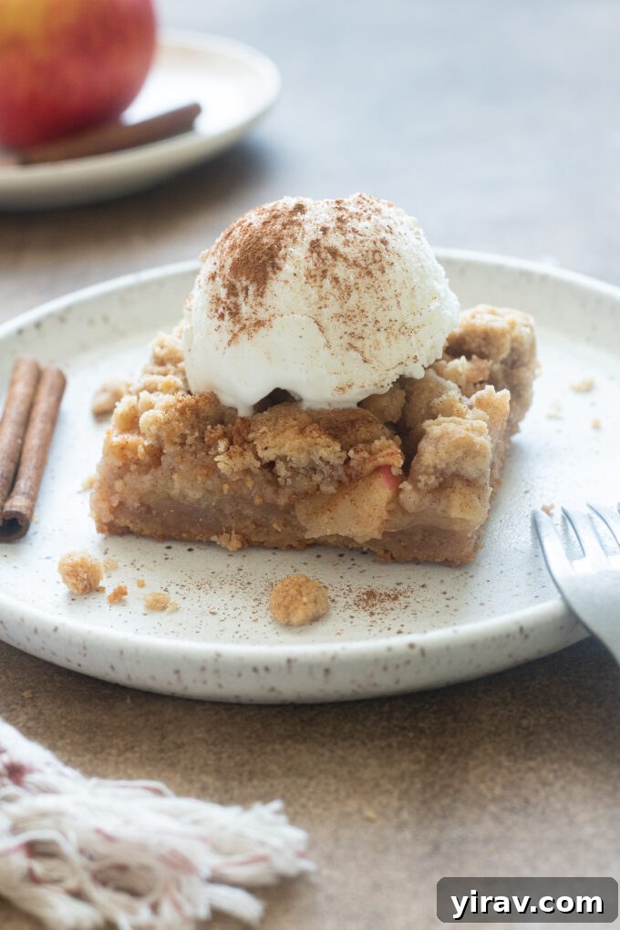 Golden Crumb Apple Pie Bars 9 Apple pie bars with vanilla ice cream and cinnamon on top, ready to be served.