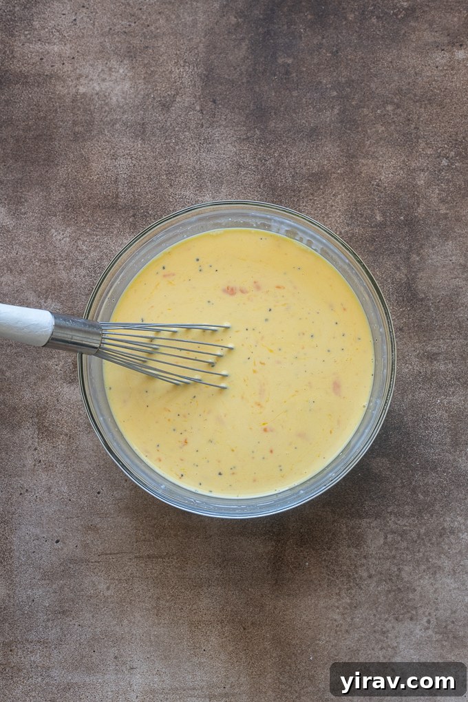 Eggs whisked with milk and parmesan cheese for sausage breakfast casserole.