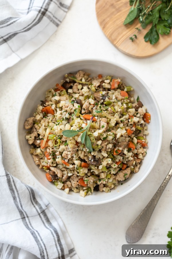 Overhead shot of low carb riced cauliflower stuffing in a serving bowl, garnished with sage.