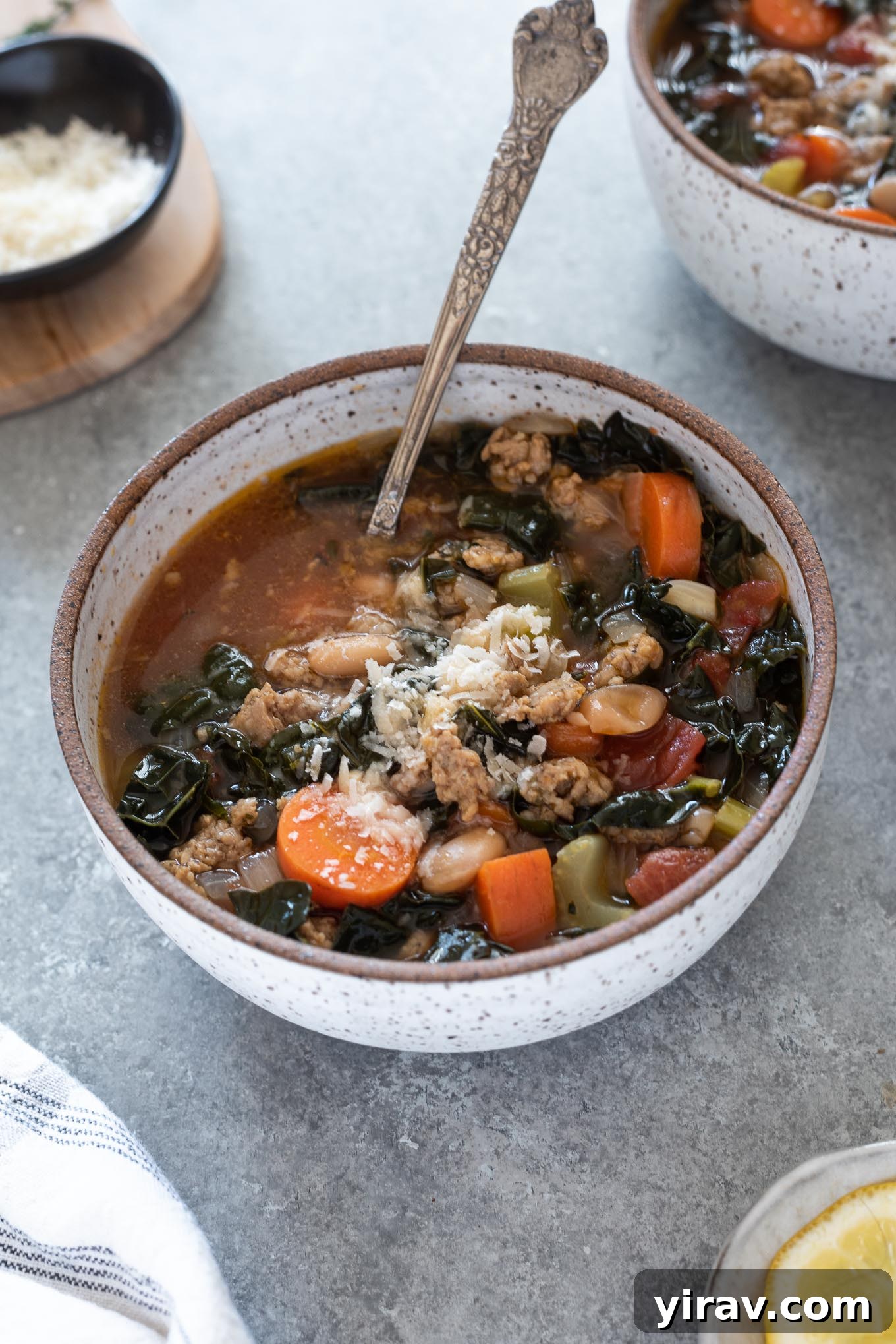 A hearty bowl of Italian sausage kale soup with a spoon.