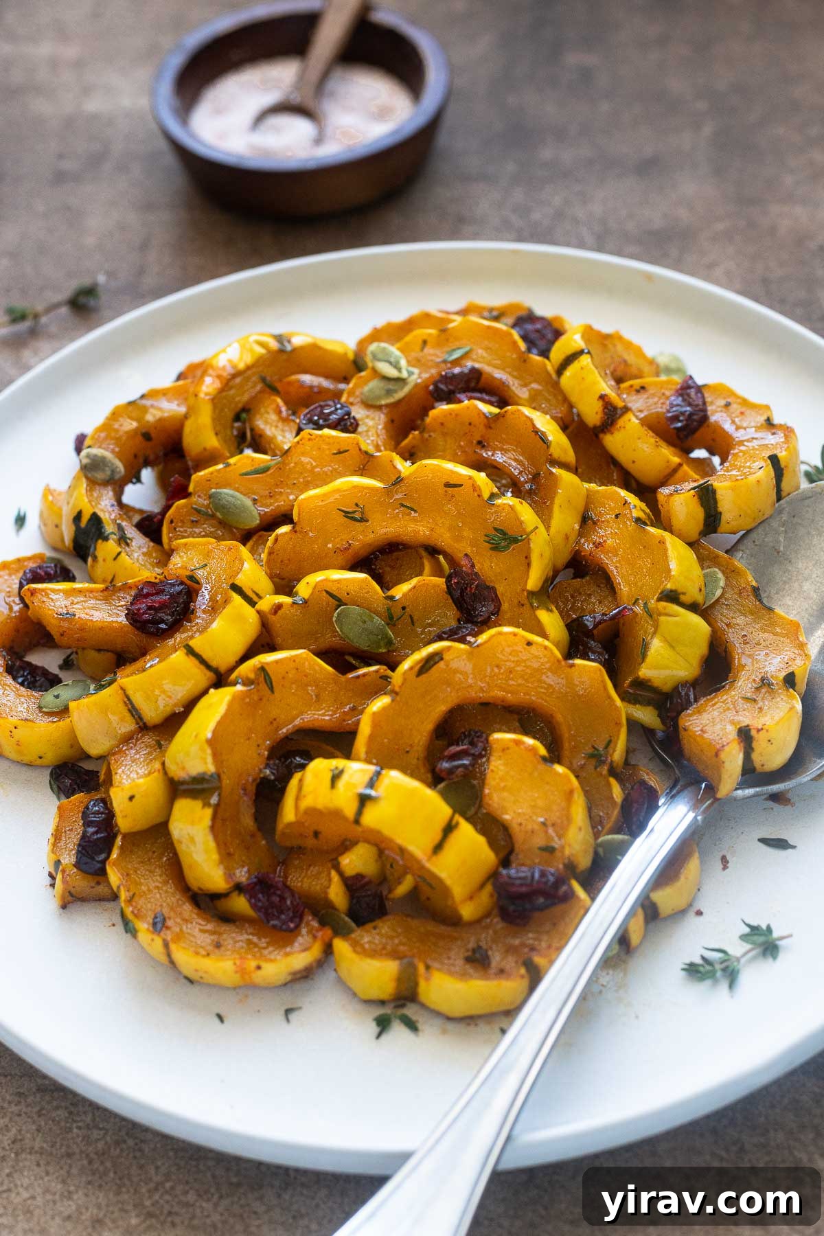 Maple roasted delicata squash on a plate with fresh thyme leaves.