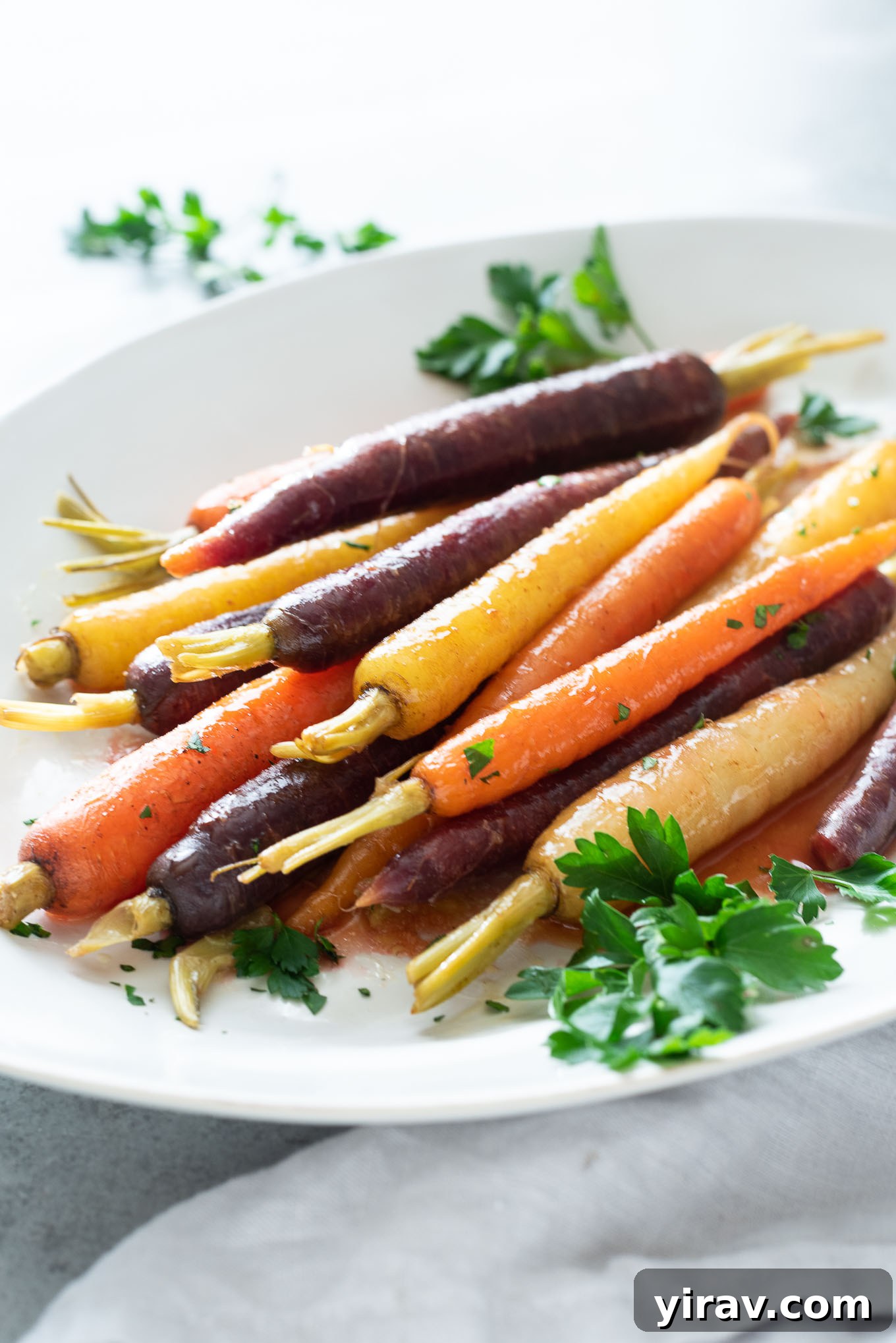 Maple glazed carrots on a platter with fresh parsley garnish.