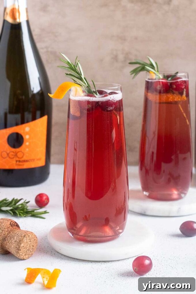Cranberry champagne cocktails with orange twist, cranberries and rosemary garnishes.