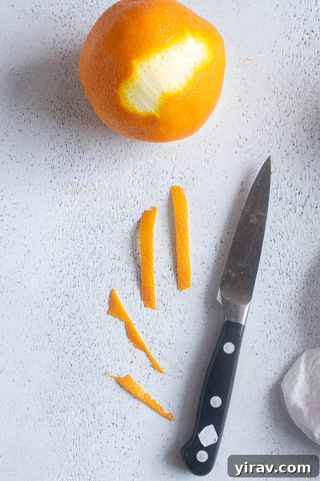 Trim orange peel into thin strips for orange twist garnish.