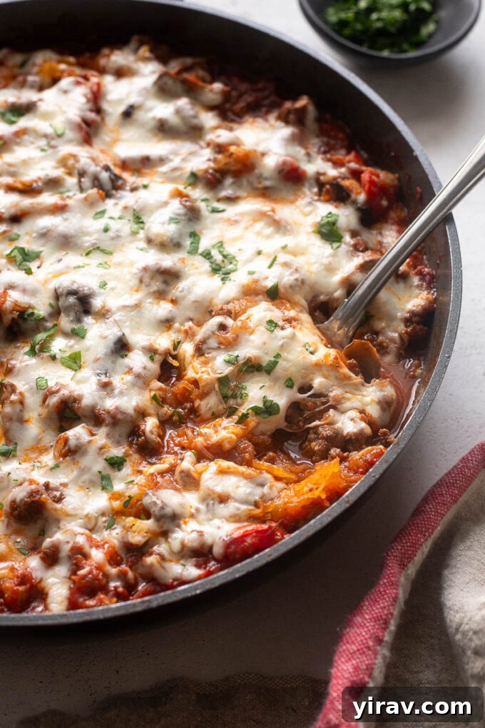 Spaghetti squash casserole in skillet with serving spoon digging in, showing the rich texture.