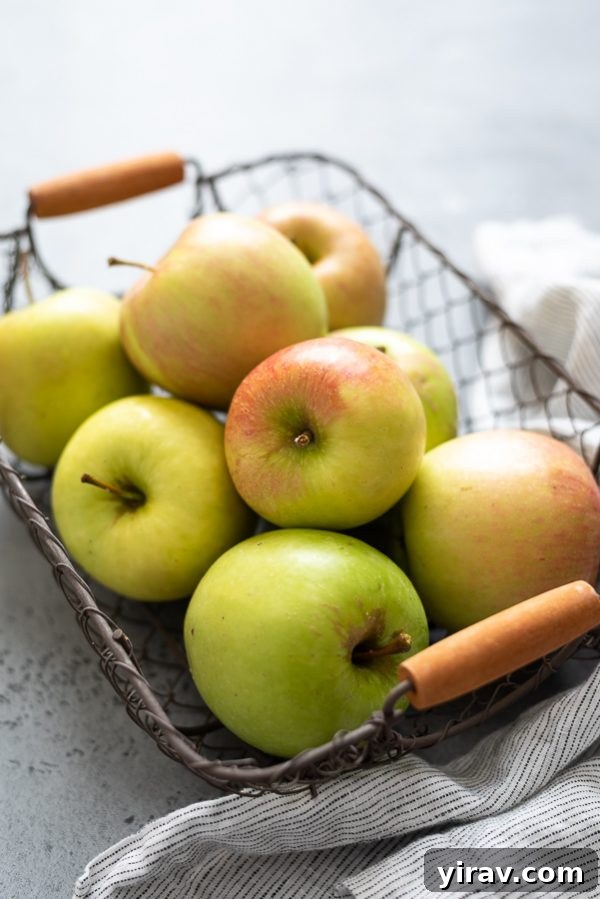A close-up shot of fresh, red apples nestled together in a rustic wire basket, symbolizing bountiful harvest and good storage.