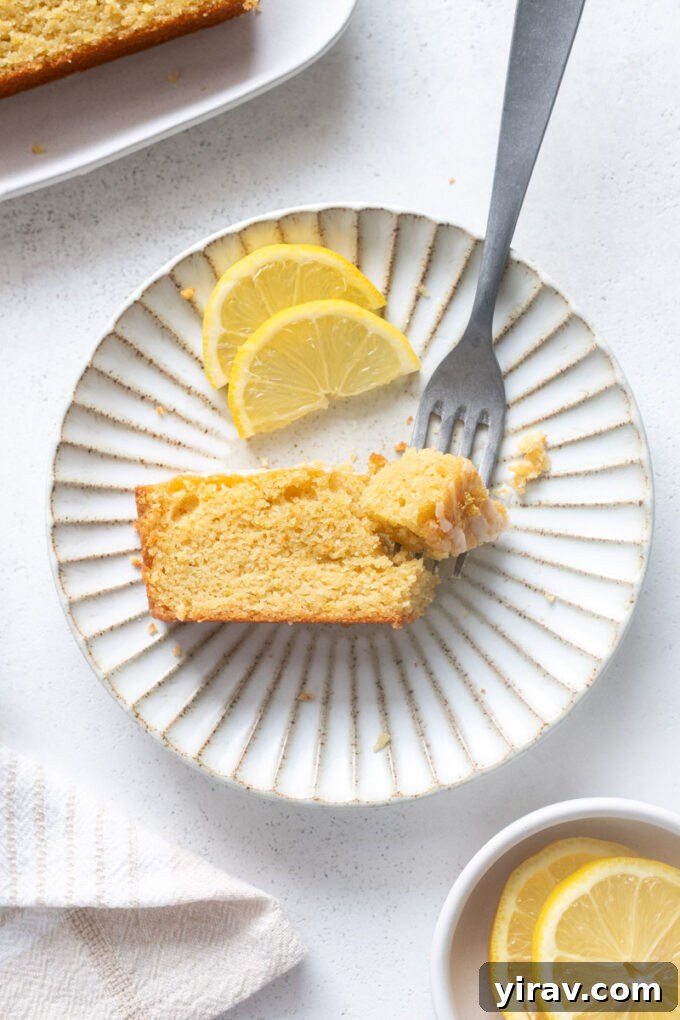 A delectable slice of almond flour lemon loaf cake with a delicate glaze, perfectly plated and ready to be savored.