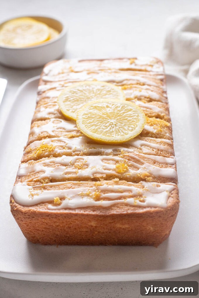 Gluten-free lemon loaf cake adorned with a sweet lemon glaze and thin slices of fresh lemon for garnish.