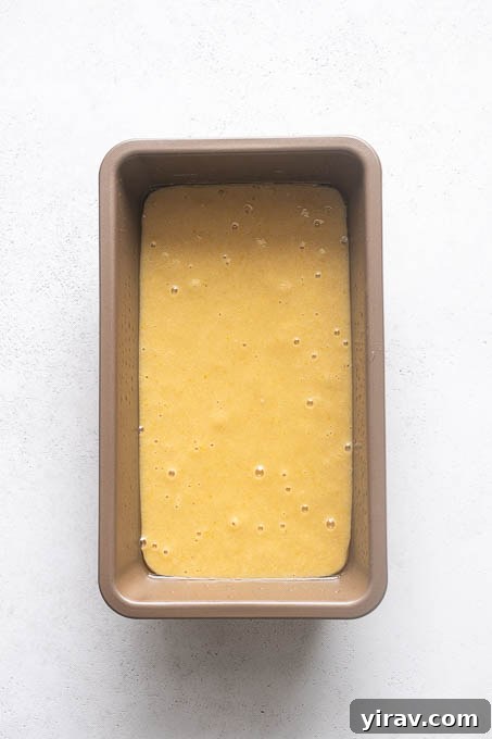 Unbaked almond flour lemon loaf cake batter in a greased loaf pan, ready for the oven.