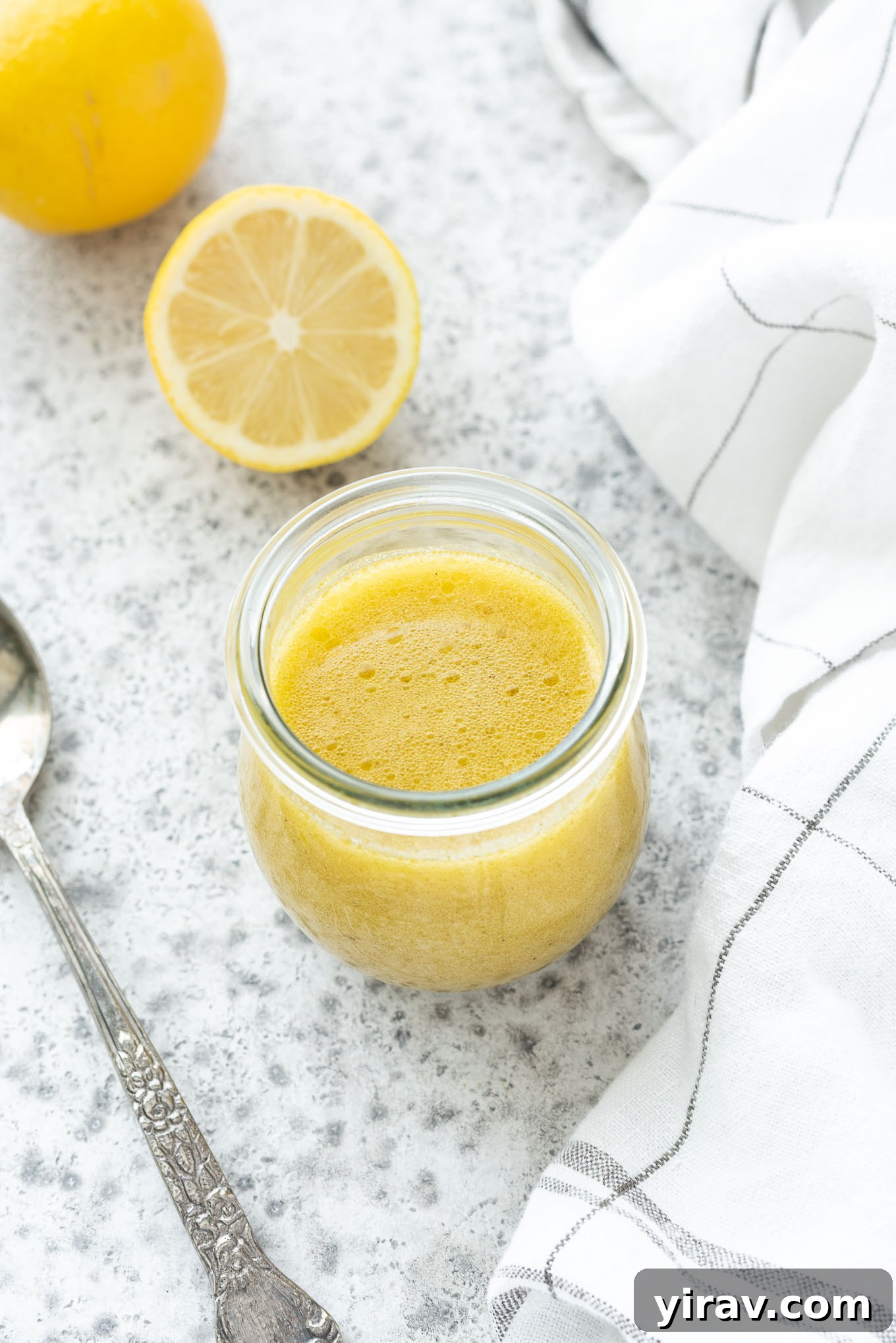 Lemon vinaigrette in a jar with a spoon nearby