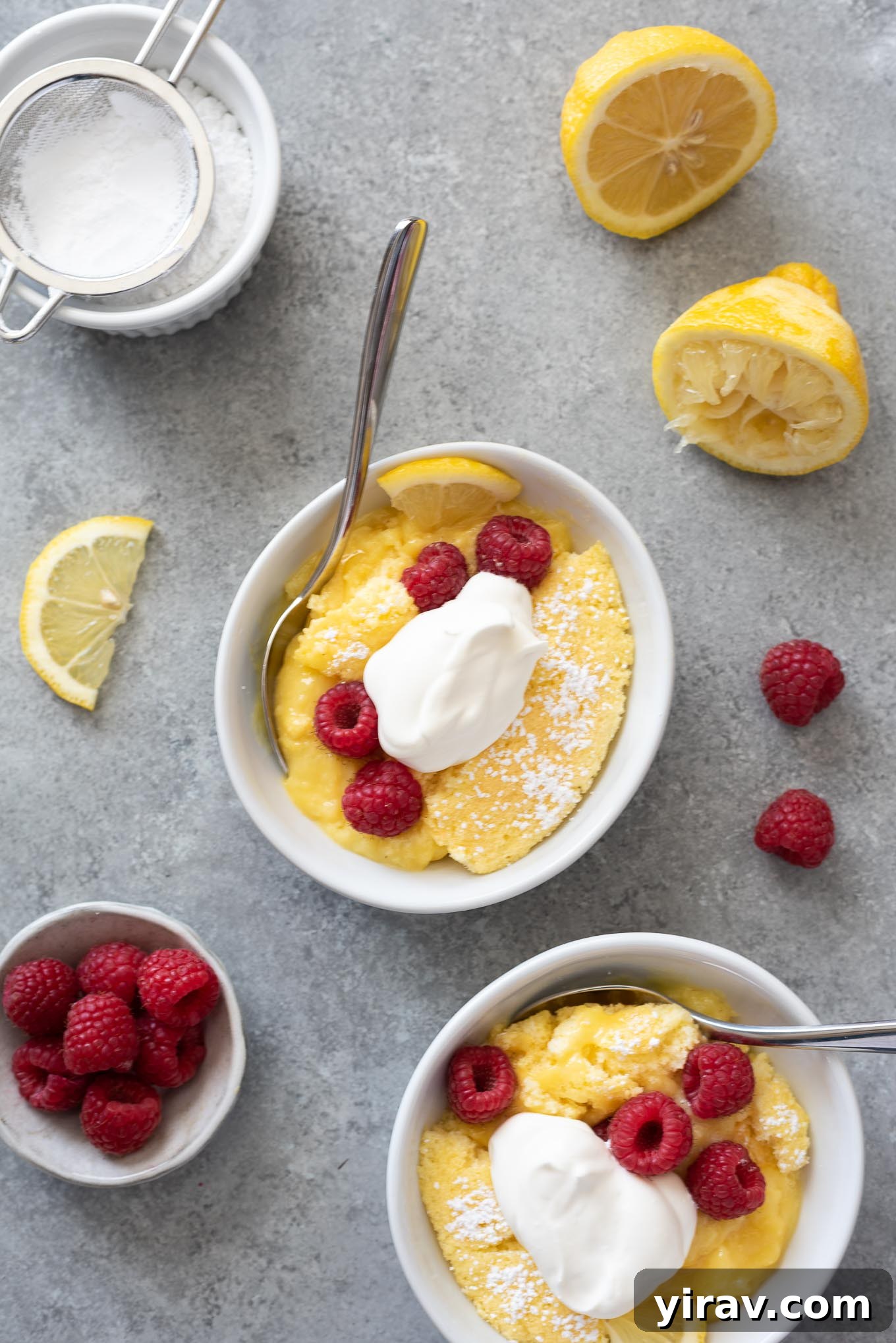 Lemon pudding cake in bowls with raspberries and whipped cream