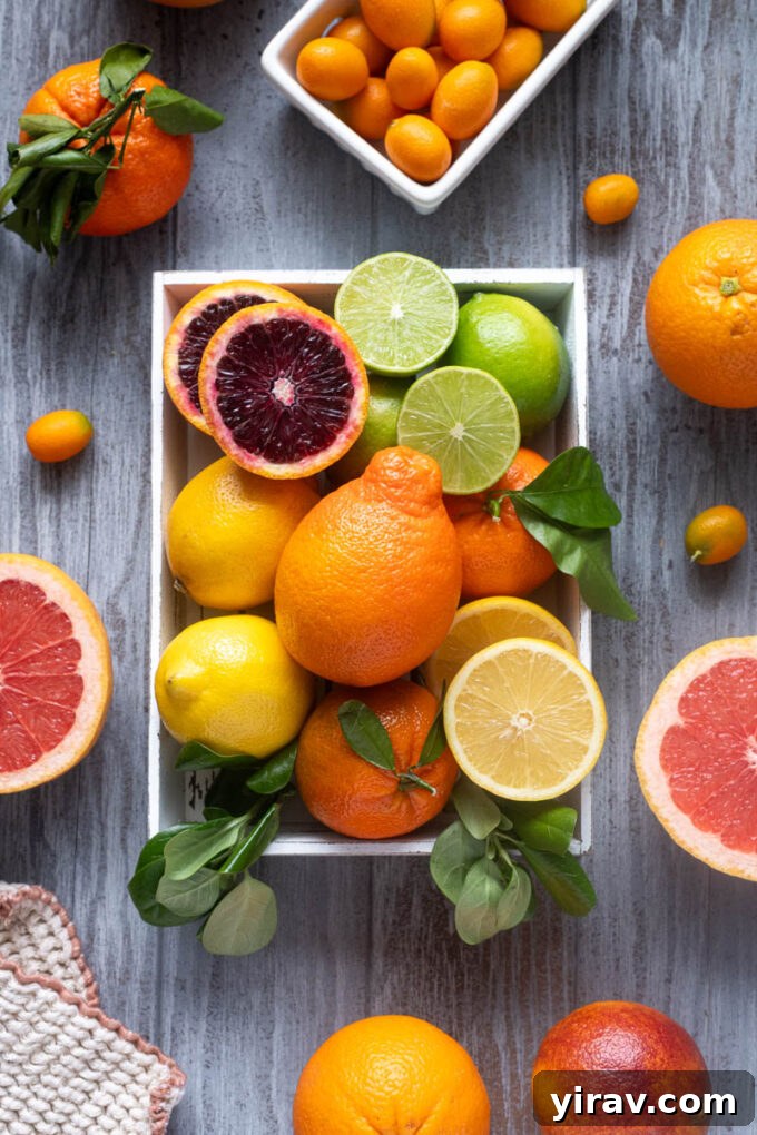 Assorted citrus fruits including blood oranges, lemons, limes and mandarins in a wooden crate.