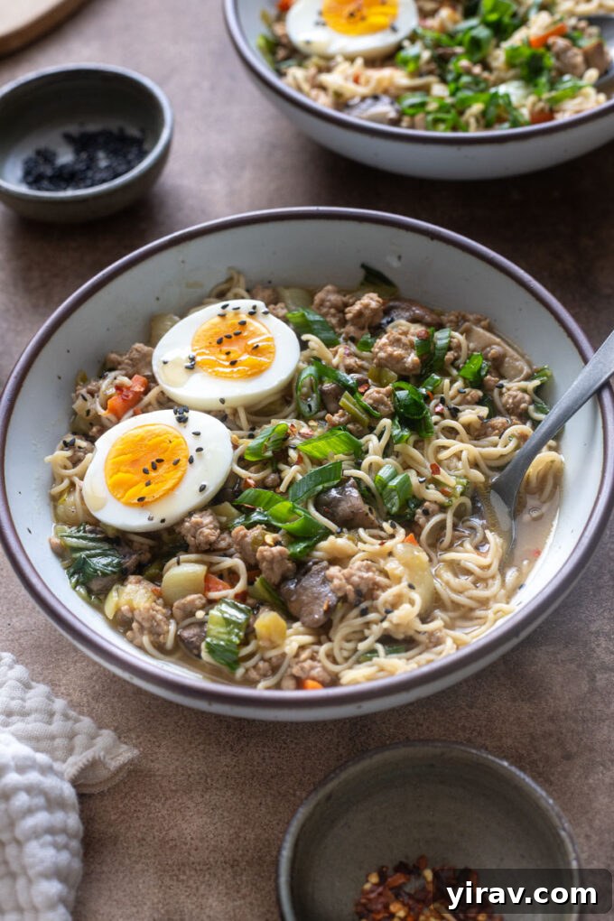 Close-up of brothy ground pork ramen with brown rice noodles and soft boiled egg.
