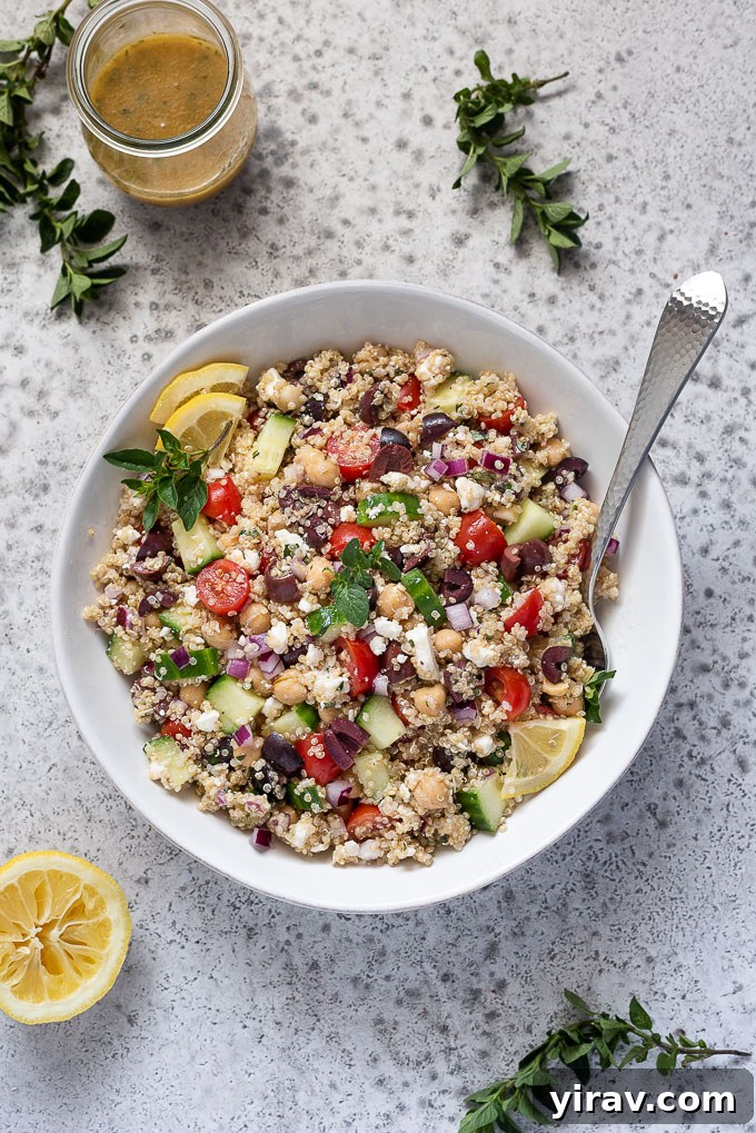 A large bowl of Greek quinoa salad served with a small bowl of Greek dressing and a sprinkle of oregano on the side.