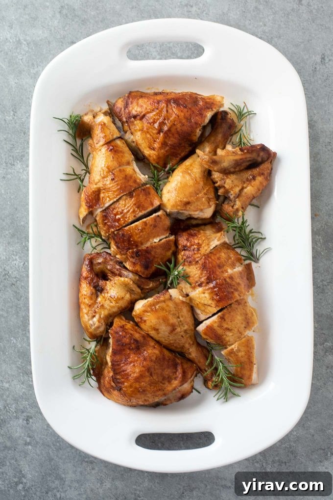 Carved spatchcock chicken on a white platter garnished with rosemary