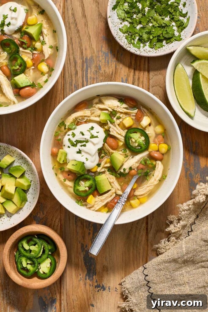 Green enchilada chicken soup in a bowl with sour cream and cilantro.