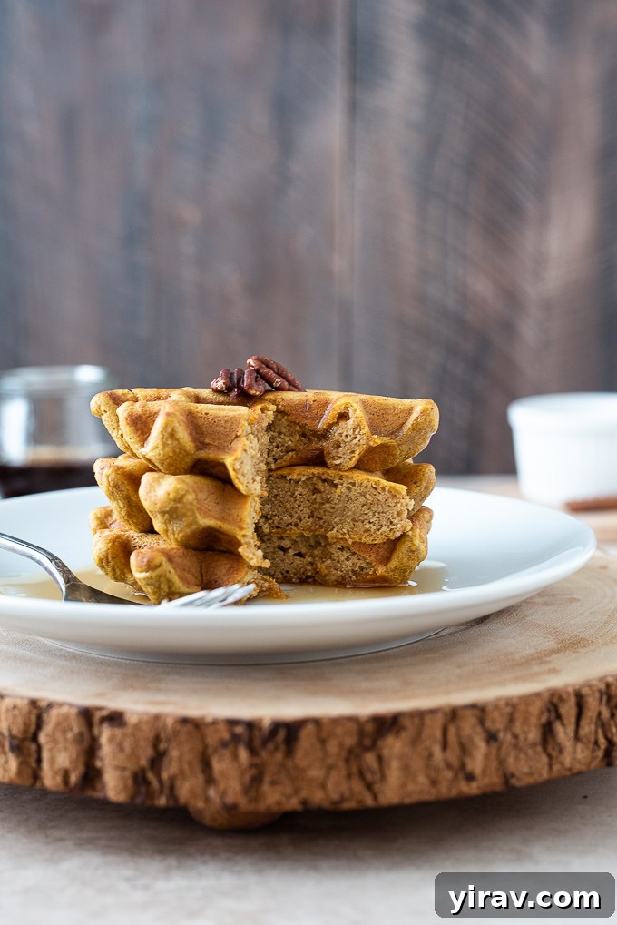 Wholesome Sweet Potato Waffles 6 Stack of sweet potato waffles sliced in half with maple syrup drizzling down, showing the fluffy interior