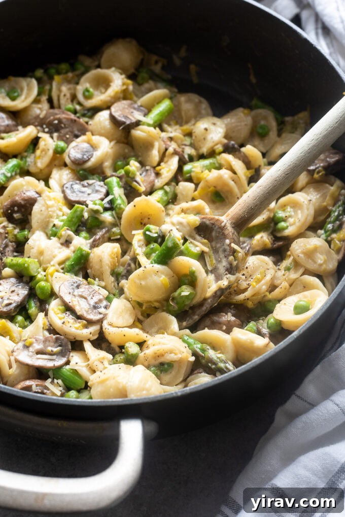 Effortless Spring Garden Pasta 9 One pot creamy vegetable pasta in a skillet with wooden spoon.