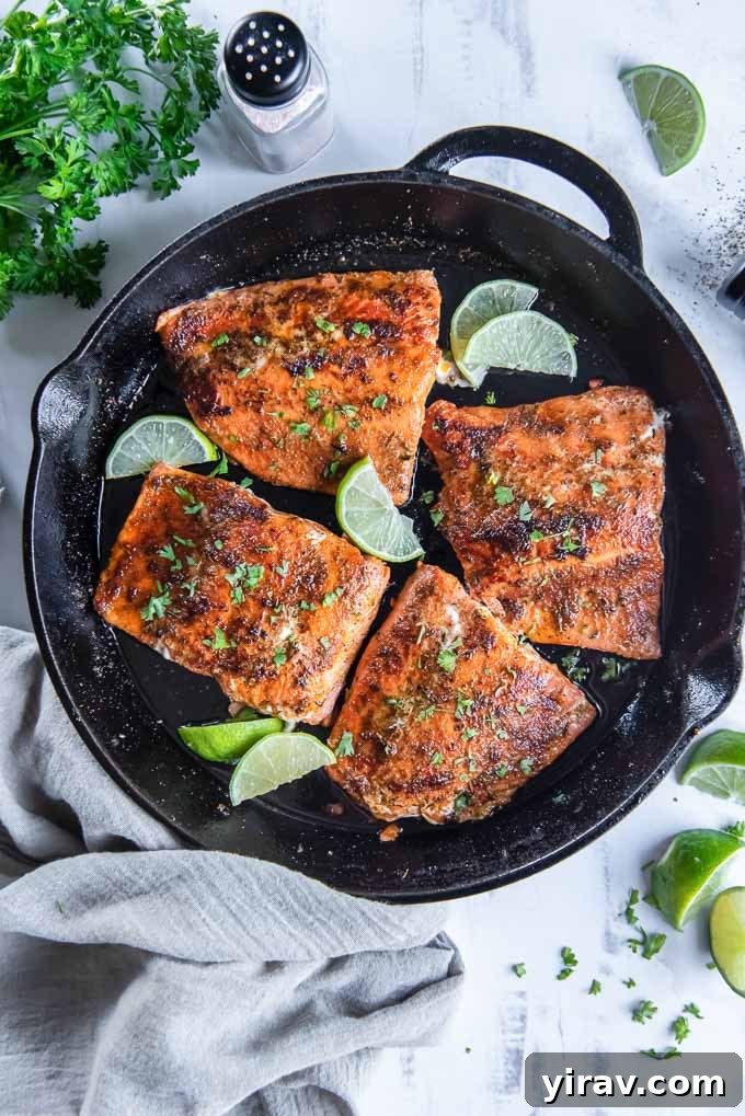 Blackened salmon filets in a cast iron skillet with limes