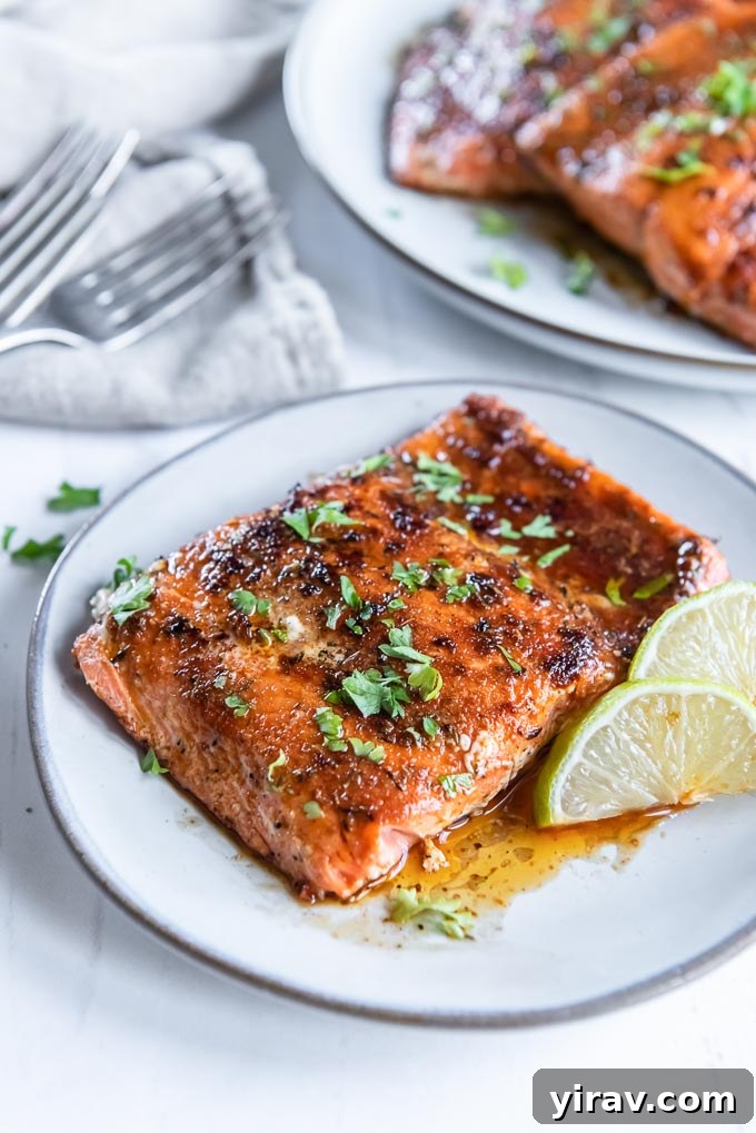 Blackened salmon filet on a white plate with parsley and lime