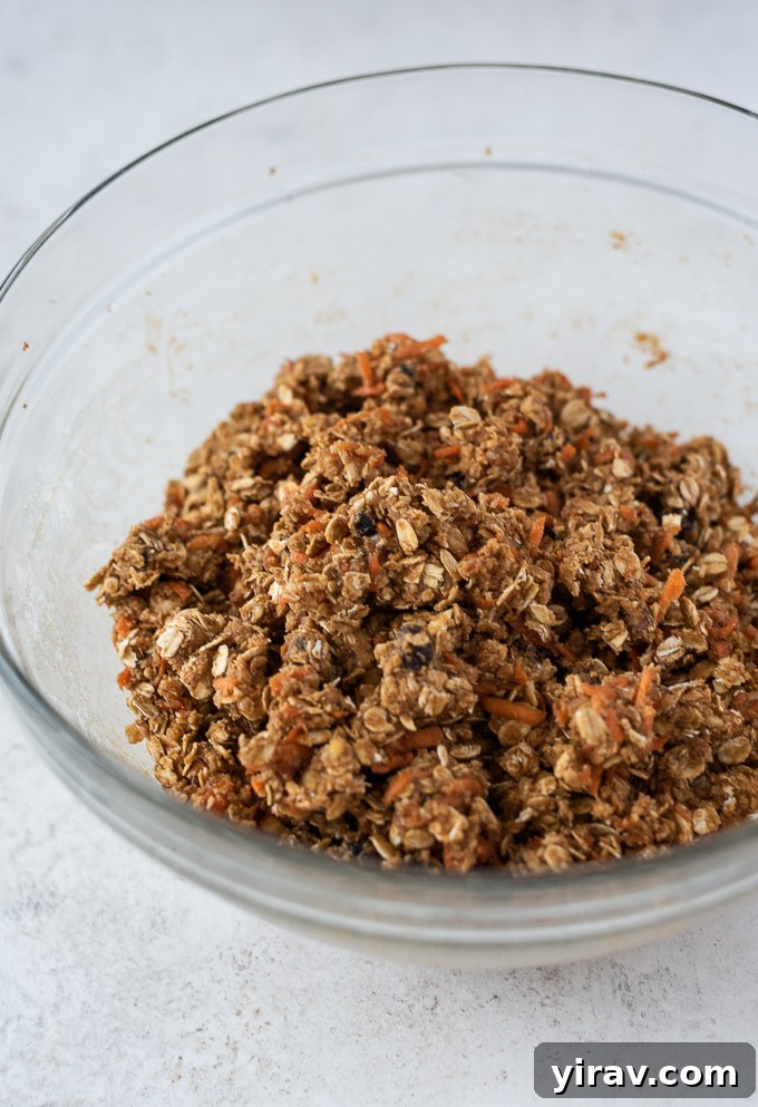 Golden Spiced Carrot Oat Cookies 6 Dry ingredients (oats, flour, spices) being added to the carrot mixture in a bowl.