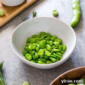 Cooked fava beans in a bowl, presented as part of a recipe card