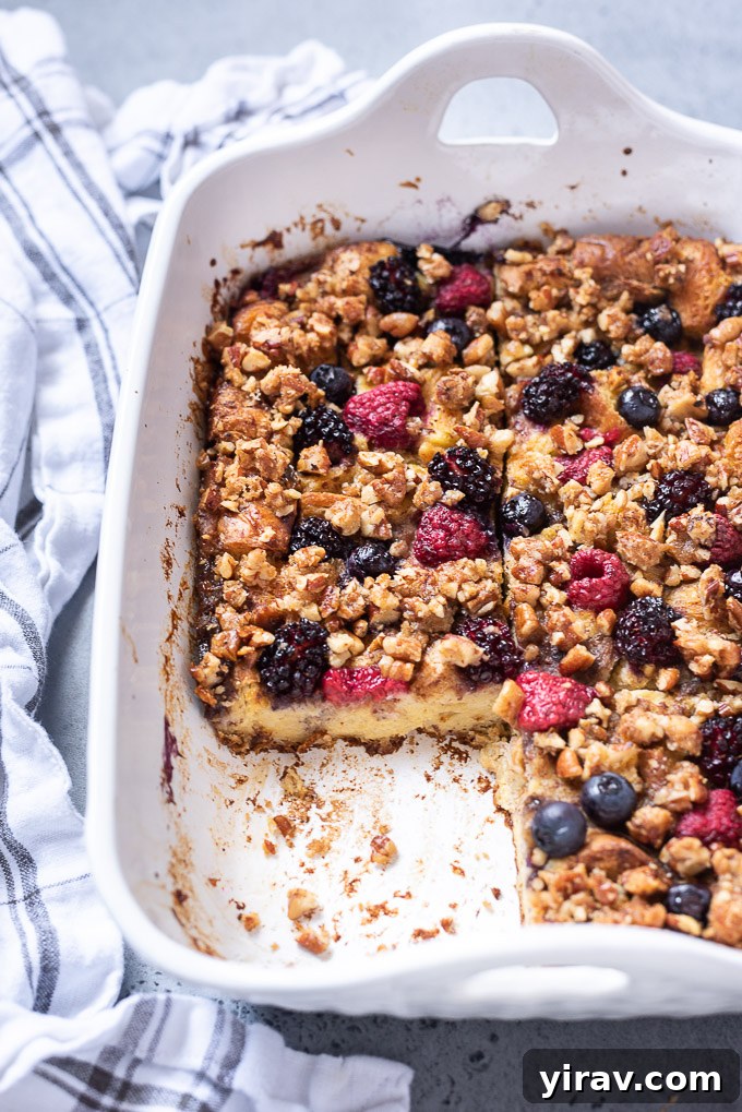 Sliced french toast casserole in a baking dish with berries on top