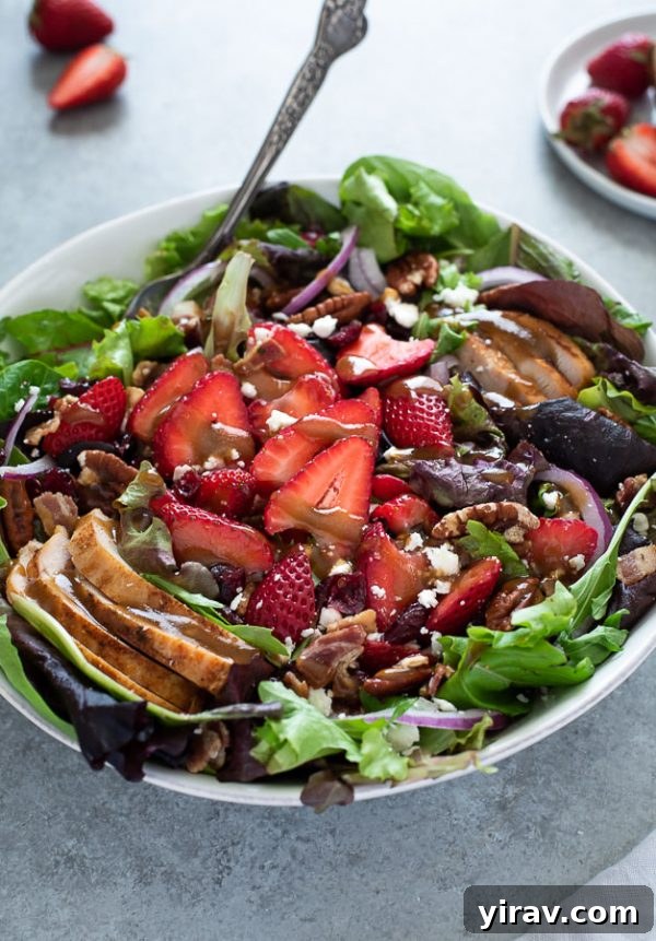 close up of strawberry fields salad with balsamic dressing on top and spoon buried inside bowl