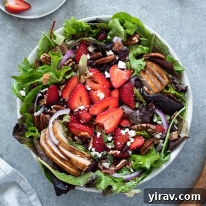 overhead shot of strawberry fields salad in white serving bowl with wooden servers