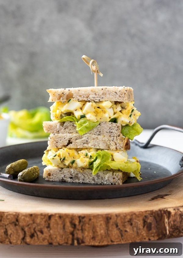Creamy Egg Salad Sandwich with fresh chives, piled high on a plate with a wooden pick