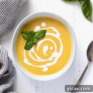 A vibrant bowl of creamy summer squash soup, elegantly swirled with coconut milk and topped with fresh basil leaves.