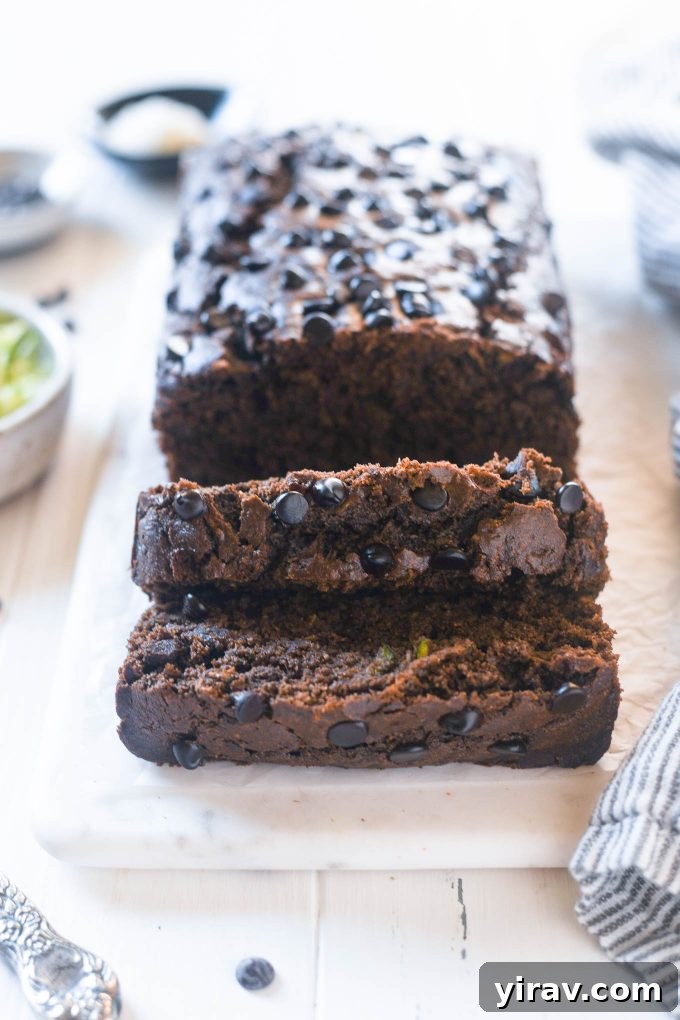 Decadent Double Chocolate Zucchini Loaf 2 A perfectly sliced loaf of Double Chocolate Zucchini Bread on a wooden board, showcasing its moist crumb and rich chocolate chips.