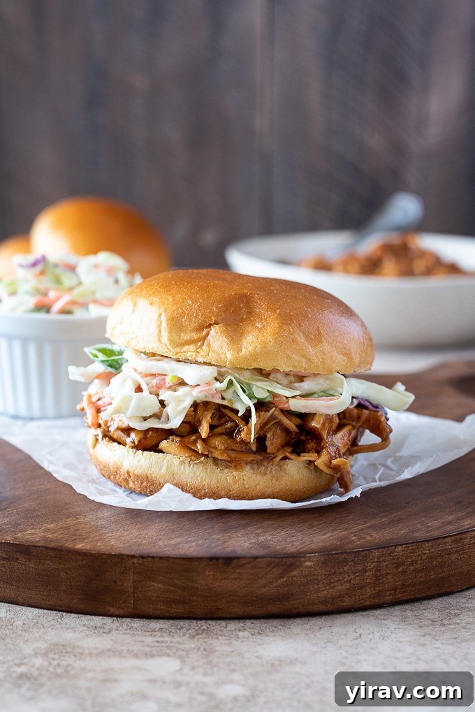 Set-It-and-Forget-It BBQ Pulled Chicken 5 BBQ pulled chicken sandwich topped with coleslaw on a wooden board
