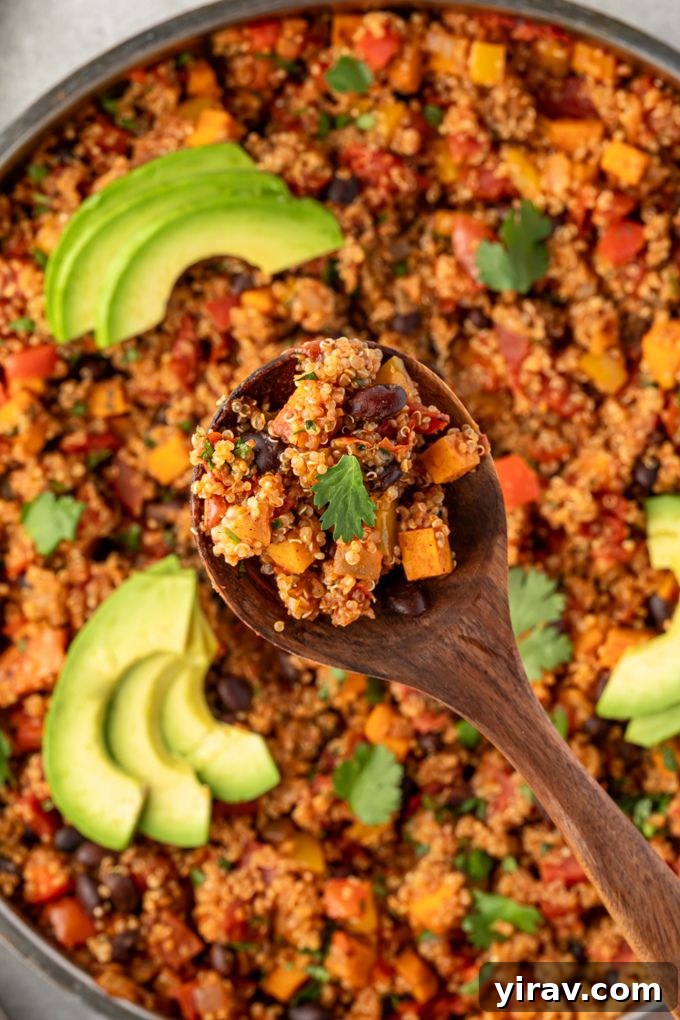 A spoonful of Mexican quinoa lifted from the pan, showing its texture and ingredients