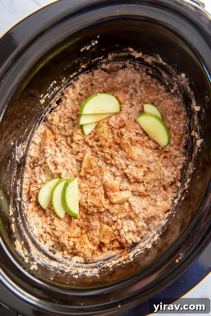 Apple Pie Slow Cooker Oatmeal 3 Slow cooker filled with apple slices and steel cut oats mixture, before cooking