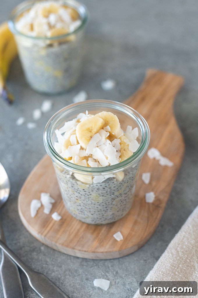 A close-up of healthy banana chia seed pudding in a glass jar, garnished with toasted coconut flakes and fresh banana slices, ready to be enjoyed.
