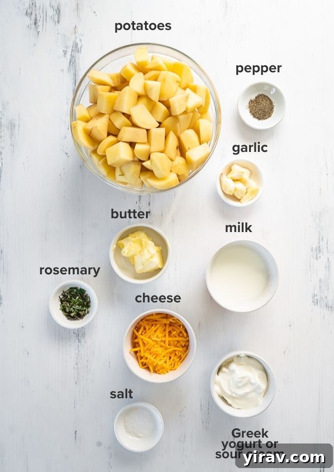 A flat lay photograph of all the ingredients needed for twice baked mashed potatoes, including potatoes, cheese, sour cream, milk, butter, garlic, and rosemary.