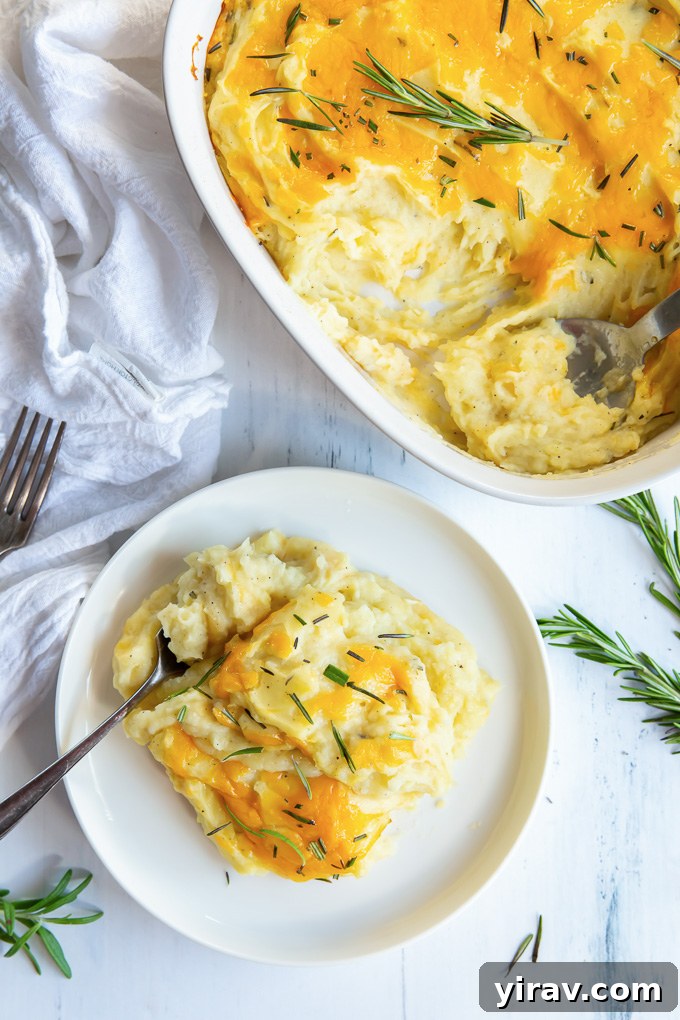 A single serving of golden brown, creamy twice baked mashed potatoes garnished with fresh rosemary on a white plate.