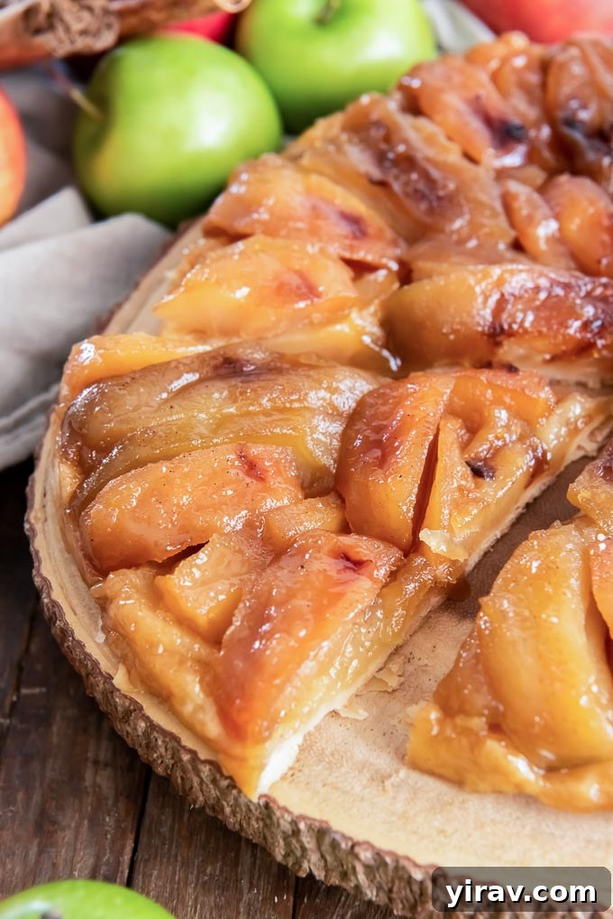 Signature Apple Tarte Tatin 6 A beautifully presented apple tarte tatin, meticulously sliced, resting on a serving platter, highlighting its caramelized apples and flaky crust.