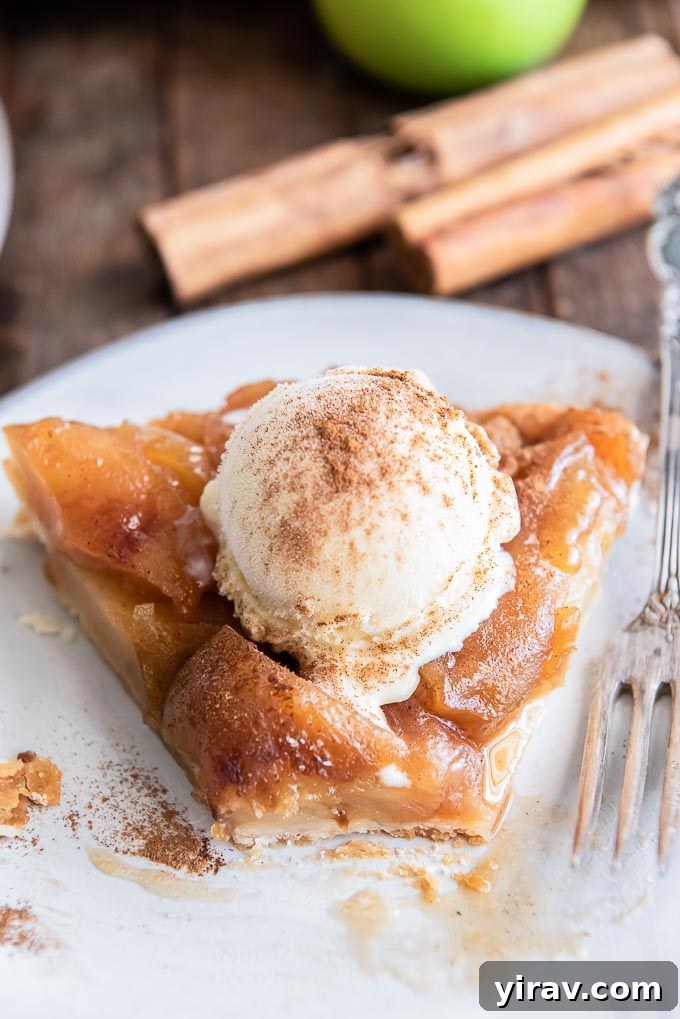 Signature Apple Tarte Tatin 7 A close-up of a slice of apple tarte tatin on a plate, with a bite taken out of it, revealing the layers of caramelized apple and flaky crust.