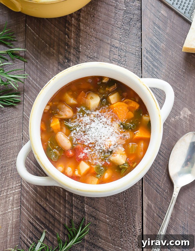 Bowl of minestrone soup in a white bowl with parmesan cheese on top