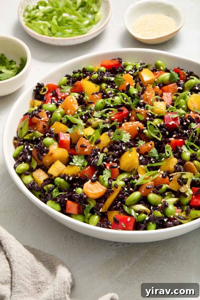 Asian black rice salad in a white serving bowl, garnished with sesame seeds.