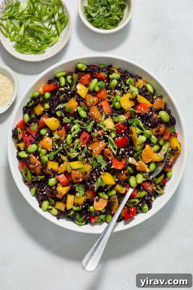Asian black rice salad in a bowl with a serving spoon, ready to be enjoyed.