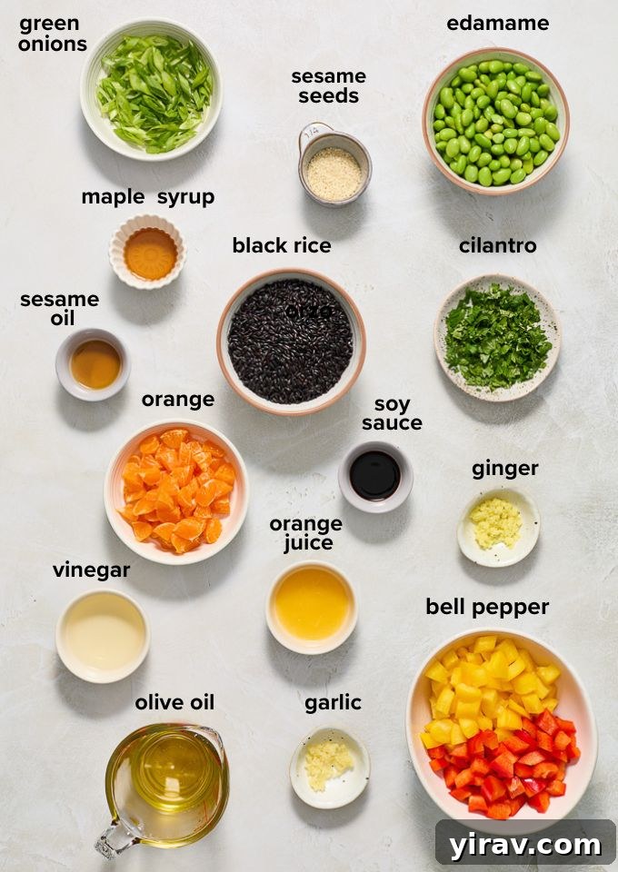 Various ingredients laid out for black rice salad, including rice, edamame, bell pepper, orange, and ginger.
